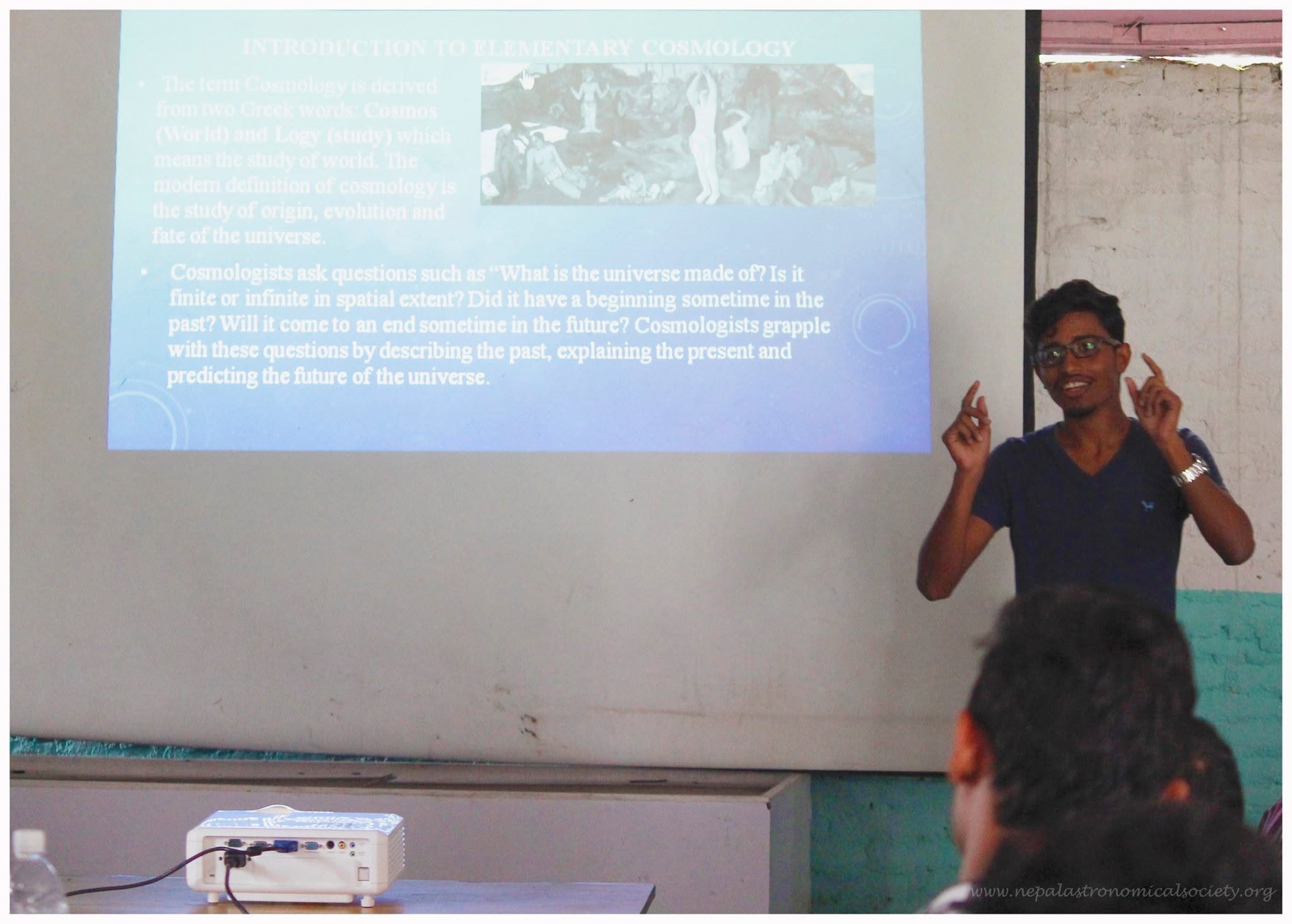 Sandeep presenting Introduction to Elementary Cosmology to an audience beside a projected slide.
