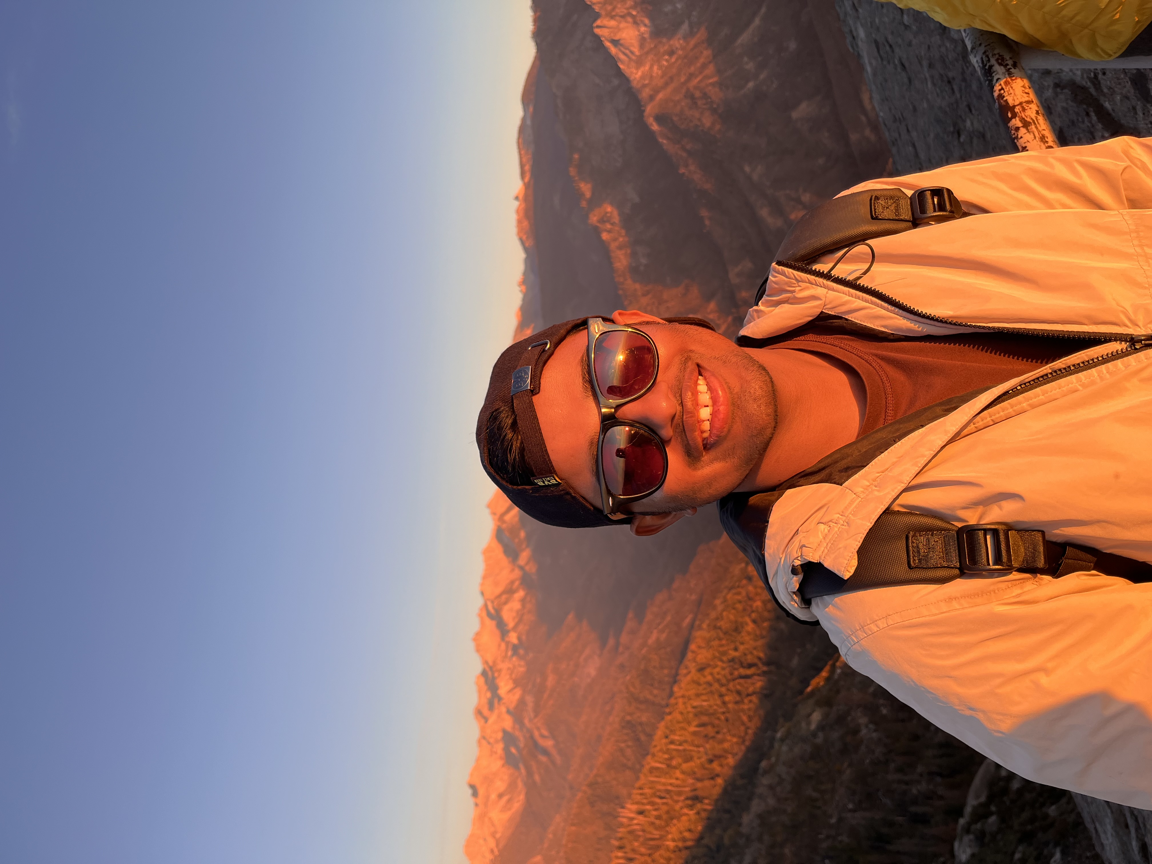 Sandeep Sharma outdoors with sunlit mountains behind him.